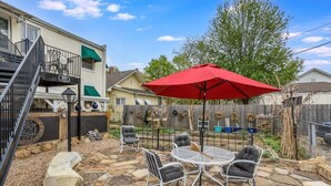 A patio with stone flooring, a red umbrella, and outdoor furniture. - Safe Area W/ Balcony - Great for Travel Nurses (Wichita)
