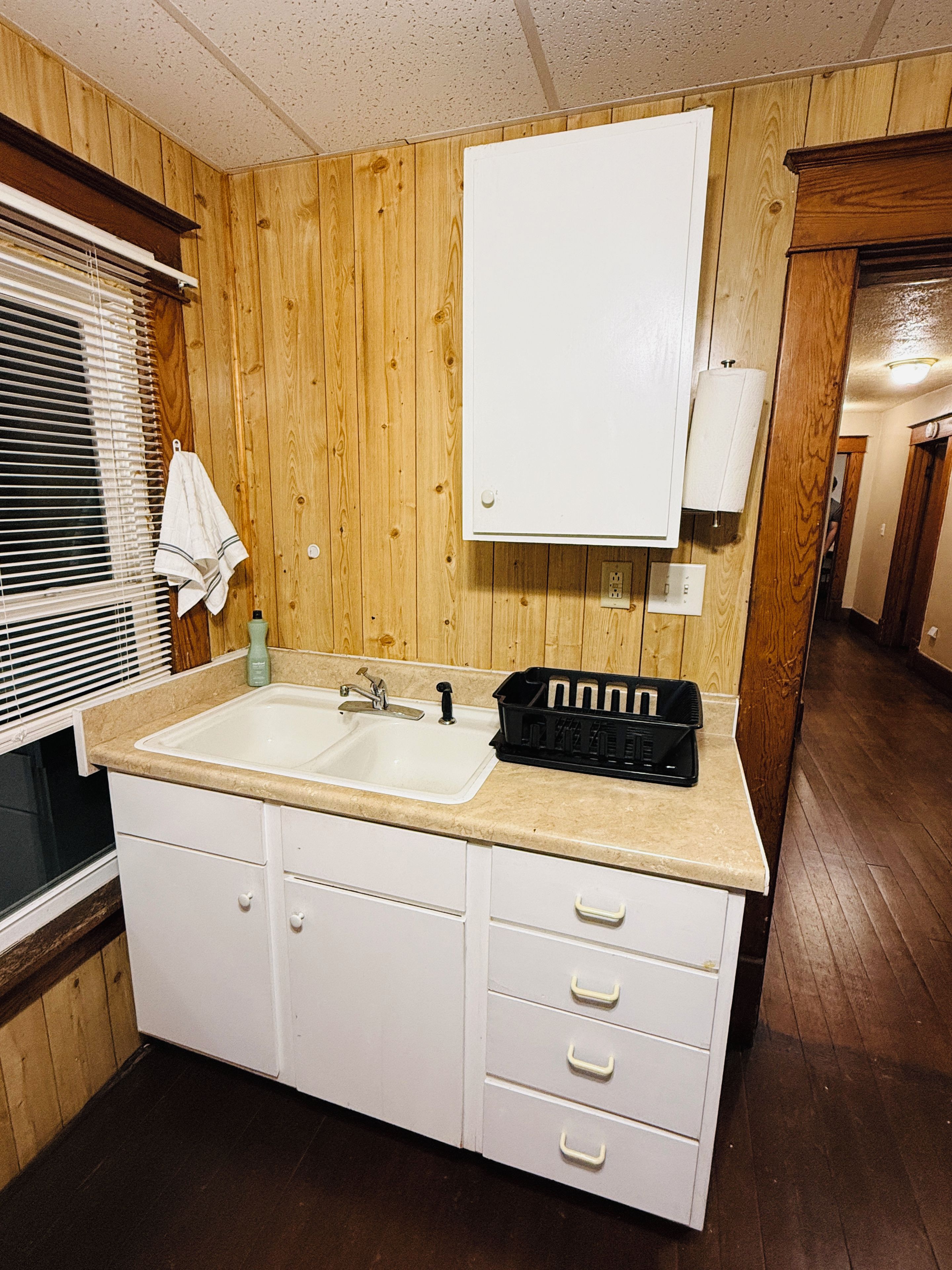 Une petite salle de bain aux dimensions réduites, avec un lambris en bois, un lavabo blanc et un miroir placé au-dessus.