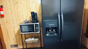 Eine Küche mit einem schwarzen Kühlschrank, einer Mikrowelle und einer Kaffeemaschine auf einer Holzausstattung.