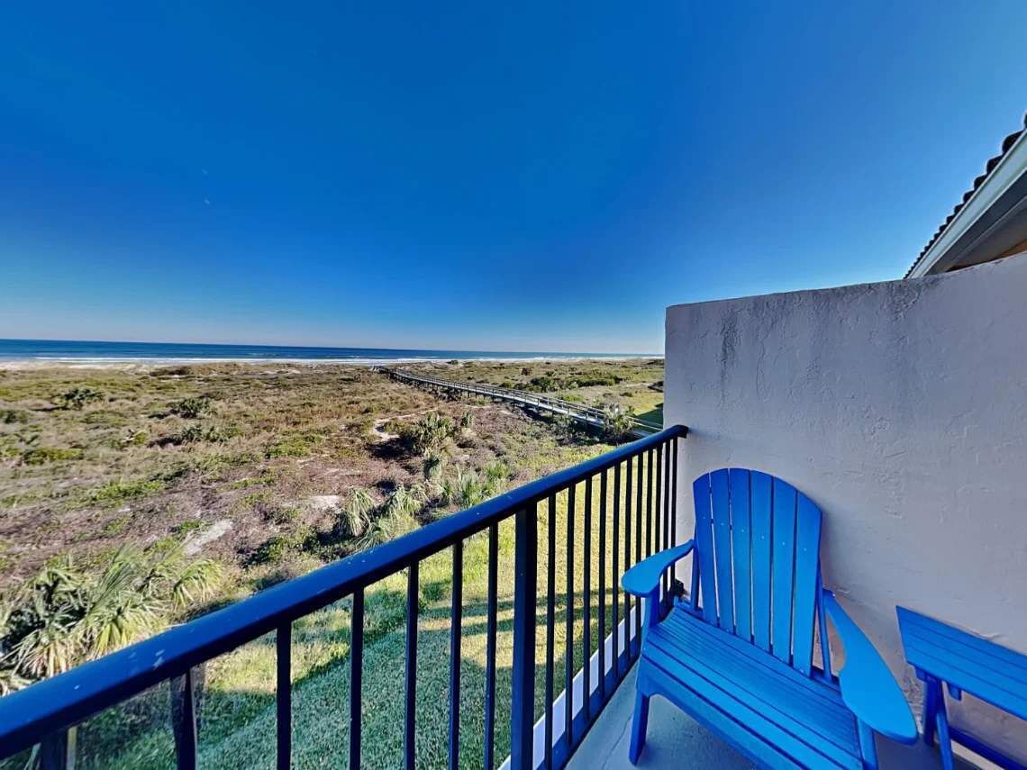 Een balkon met uitzicht op een strand en een spoorlijn.