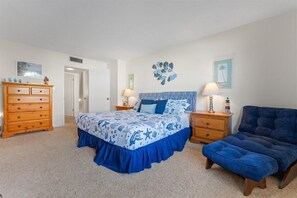 Une chambre à coucher avec un lit, une commode, une chaise et des œuvres d’art murales.