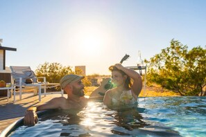 A couple relaxing in a hot tub with a guitar and a bottle in the background. - Friendship House | 5 Acres | Secluded | Hot Tub (Twentynine Palms)