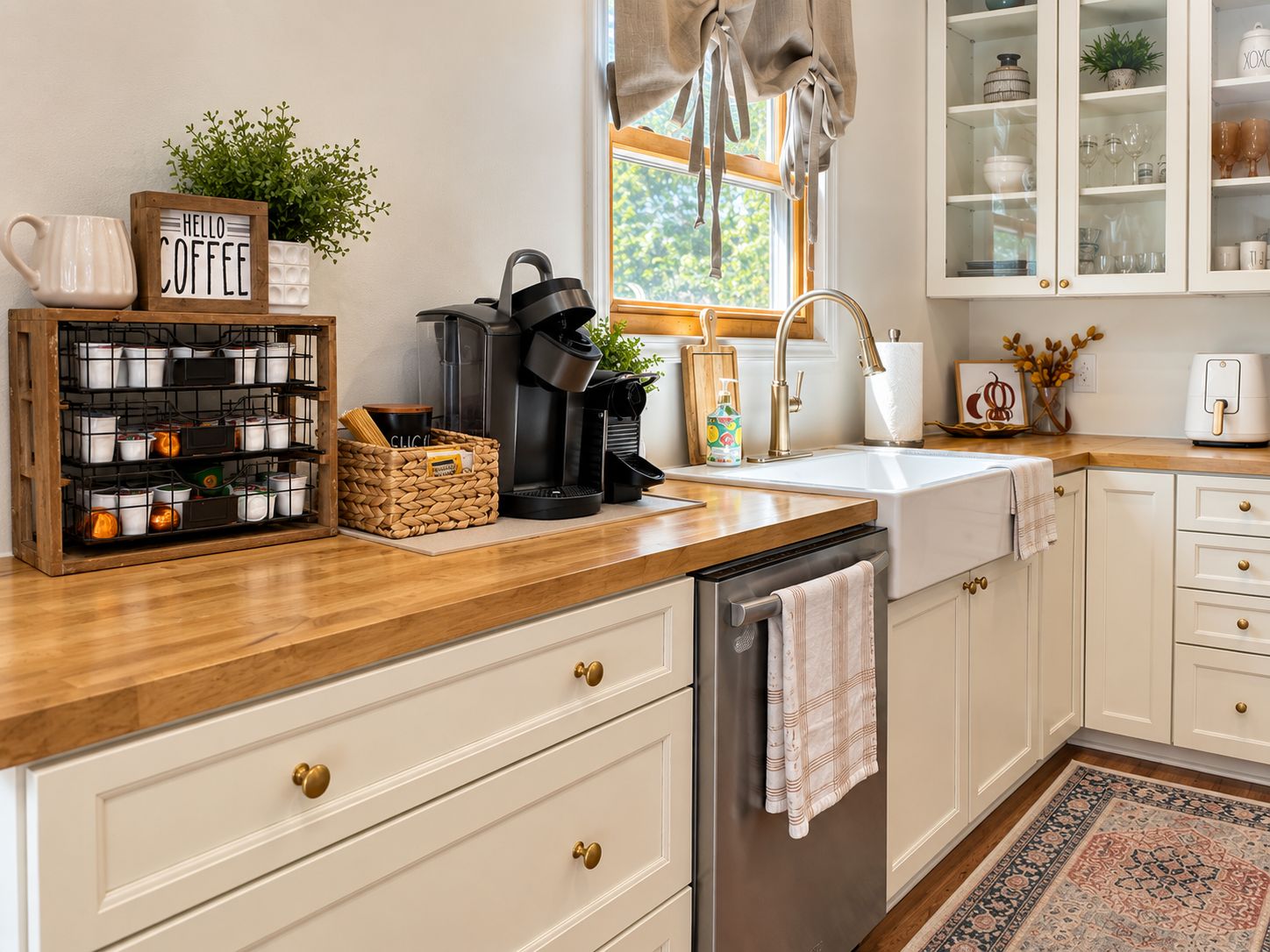 A kitchen with a wooden countertop, white cabinets, a coffee maker, and a window with curtains.