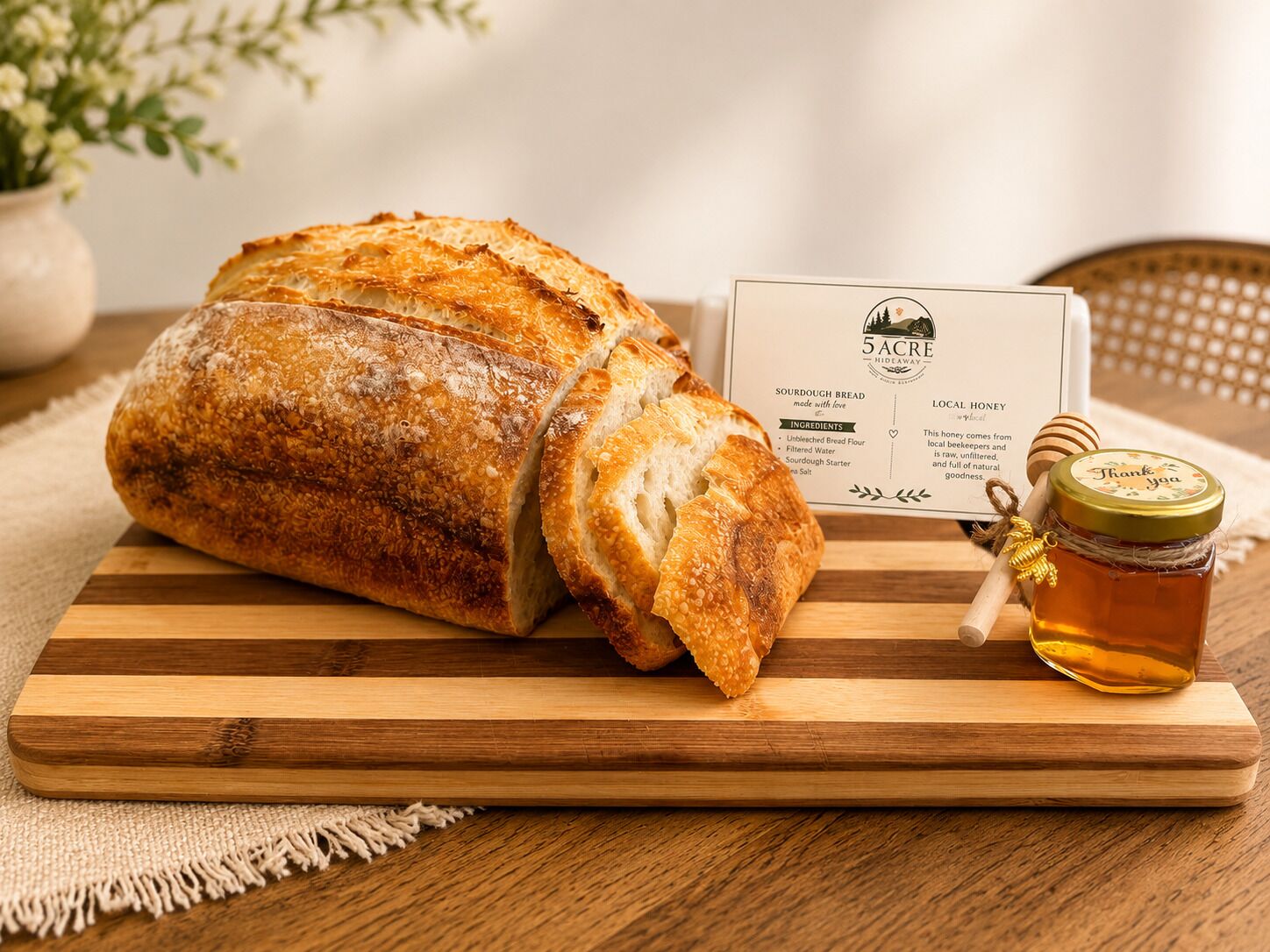 Ein Laib Sauerteigbrot auf einem Holzschneidebrett mit einem Honigglas und einer Karte daneben.
