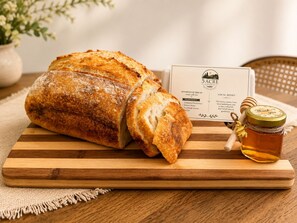 A loaf of sourdough bread on a wooden cutting board with a honey jar and a card beside it. - Private Pool Retreat- Fire Table + Country Escape in Cleveland TN (Cleveland)