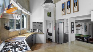 A modern kitchen with a gas stove, a sink, and a window. There is a dining area with a pool table and a refrigerator. - Iconic property • Spectacular outlook (Raglan)