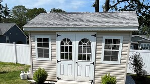 A single-story house with a front porch, two windows with arched tops, and a small front yard with a potted plant. - Family-Friendly Wells, Maine Vacation Home Near Ogunquit & Beaches (Wells)