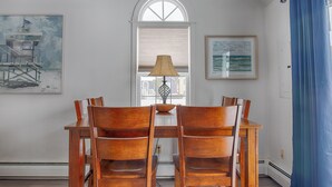 A dining area with a table and four chairs, a lamp, a window with blinds, and two framed pictures on the wall. - Family-Friendly Wells, Maine Vacation Home Near Ogunquit & Beaches (Wells)