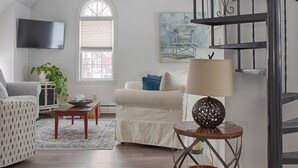 A spacious living room with a modern staircase, a flat-screen TV mounted on the wall, a comfortable sofa, and a decorative lamp. - Family-Friendly Wells, Maine Vacation Home Near Ogunquit & Beaches (Wells)