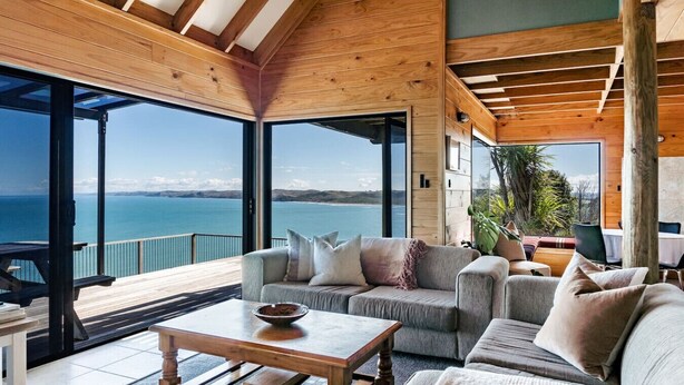 Ein geräumiges Zimmer mit großem Fenster zum Meer, Holzboden und einer gemütlichen Sitzecke mit Couchtisch.