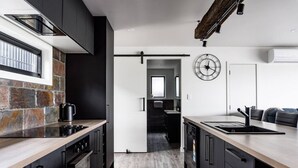 Eine moderne Küche mit dunklen Schränken, einer Arbeitsplatte aus Stein und einer Holzausziehtafel.