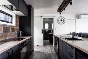 Eine moderne Küche mit dunklen Schränken, einer Arbeitsplatte aus Stein und einer Holzausziehtafel.