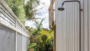 Um deck de madeira estreito leva a um edifício branco com chuveiro.