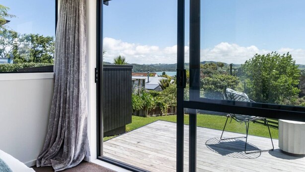 Varanda com vista para um lago e colinas, um deck de madeira e uma porta de vidro.