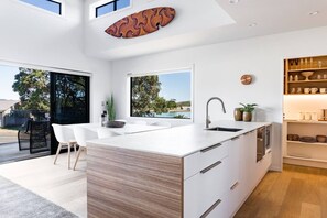 Cocina moderna con una isla grande, armarios blancos y vistas al exterior.