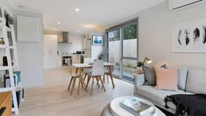 Ein modernes Wohnzimmer mit Sofa, Couchtisch und einem Essbereich mit Stühlen und Tisch.