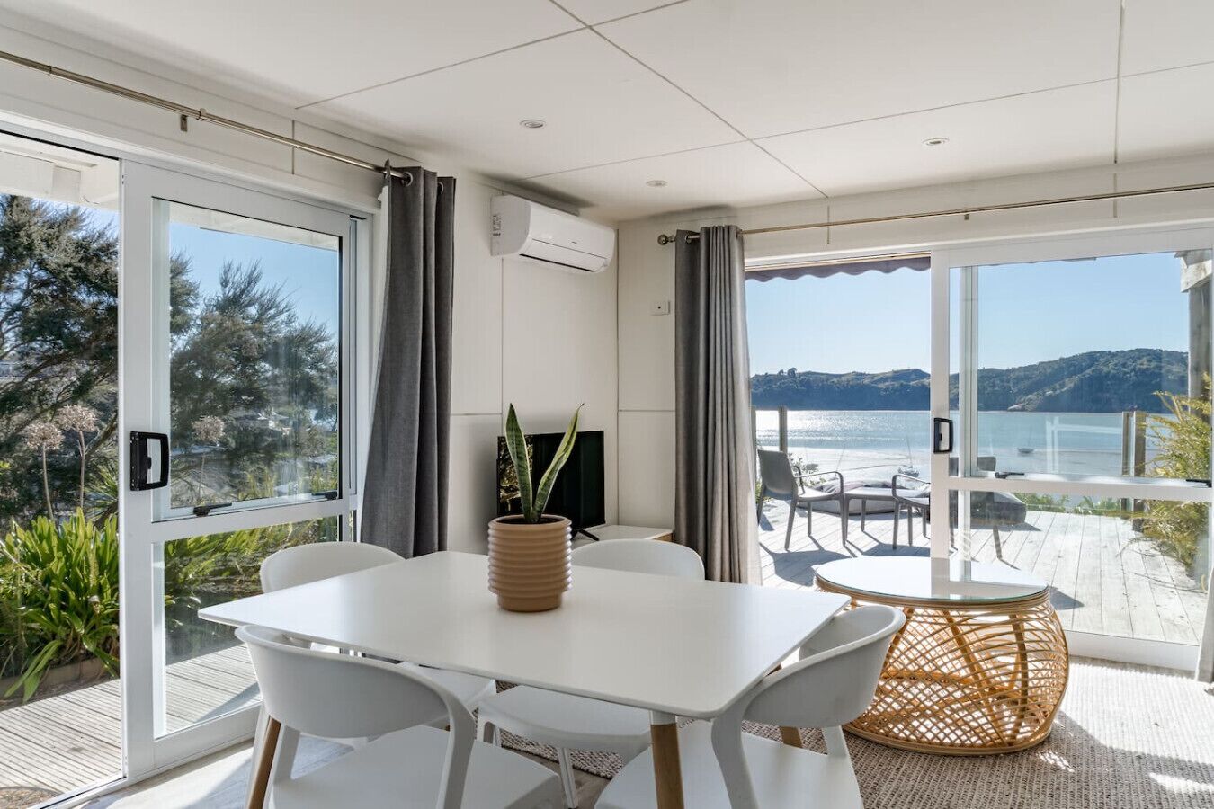 Una habitación moderna con un amplio ventanal corredera que da a un balcón con vista al mar.