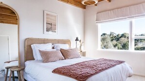 Ein Schlafzimmer mit Bett, Nachttisch, Fenster mit Aussicht und Holzboden.