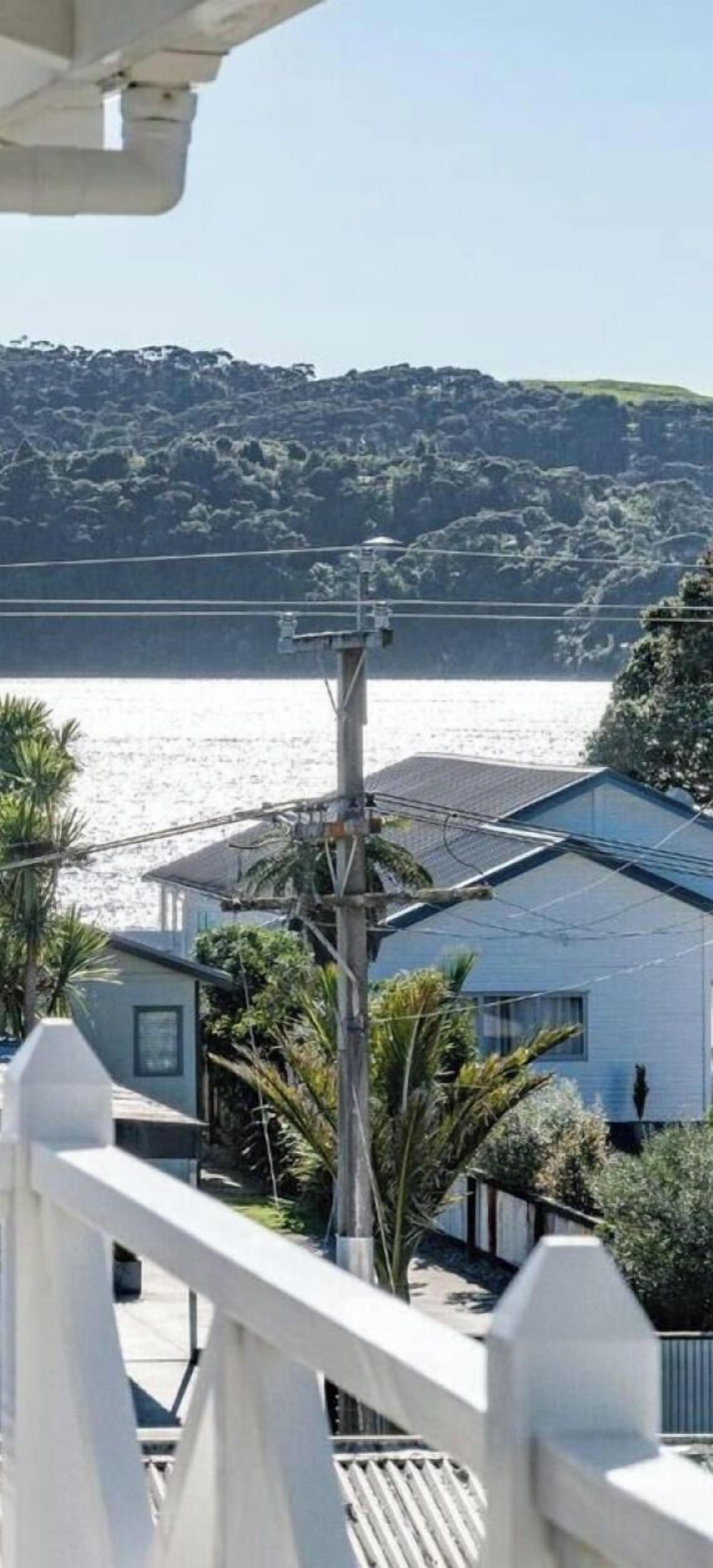 A residential area with a view of a body of water, a utility pole, and a house with a sloped roof.