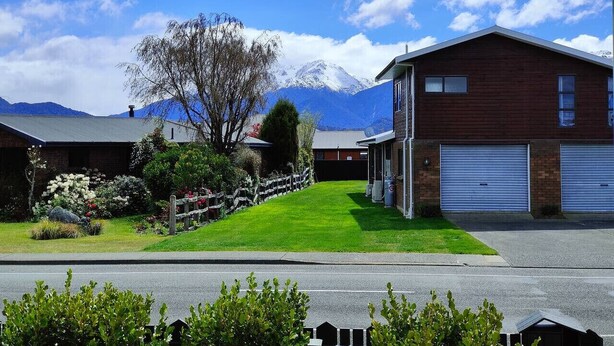 A residential area with a house featuring a garage, a well-maintained lawn, and a mountain backdrop.