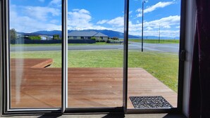 A view through a sliding glass door with a wooden deck and a doormat. - Fiordland Family Favourite (Te Anau)