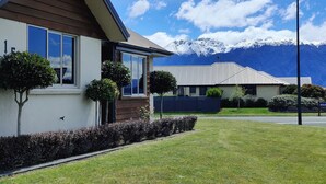 A modern house with a sloped roof, large windows, and a well-maintained lawn. - Fiordland Family Favourite (Te Anau)