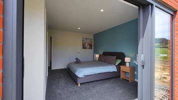 A bedroom with a bed, nightstands, and a sliding glass door leading to an outdoor area.