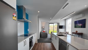 A modern kitchen with white cabinets, a blue range hood, and a grey countertop. - Rack n Relax Riverton (Riverton / Aparima)