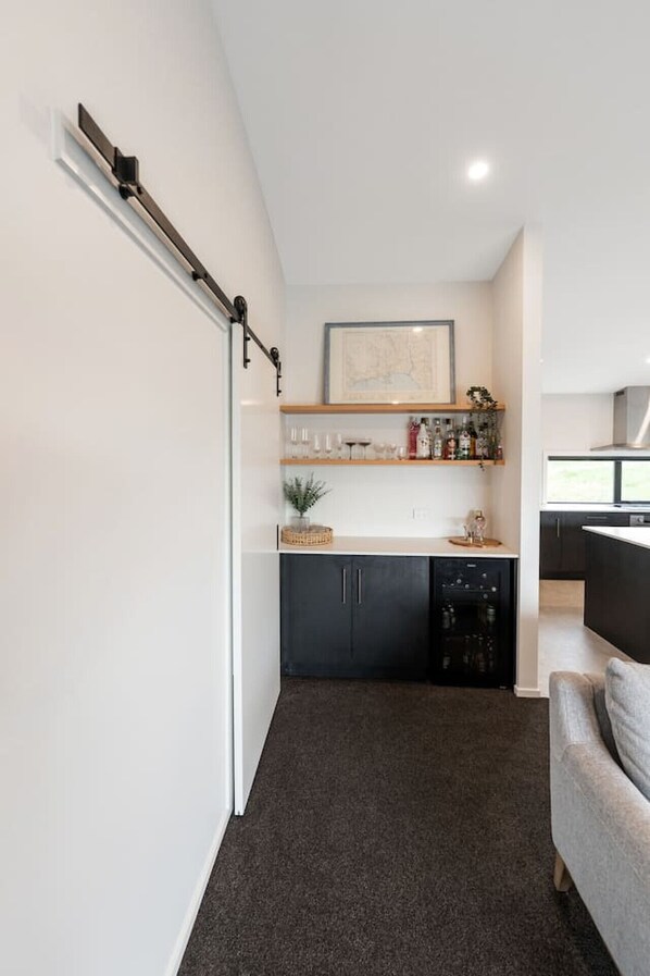 A compact kitchen with dark cabinets, a dishwasher, and a countertop with various items.