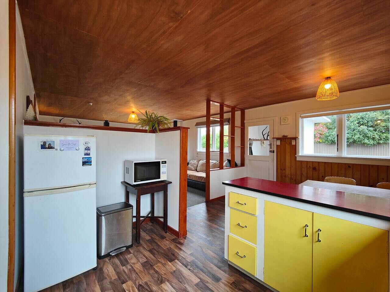 A compact kitchen with a refrigerator, microwave, and yellow cabinets.