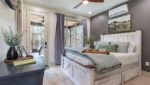 A bedroom with a bed, bedside table, and a ceiling fan. - Modern Black Cabin w/ Hot Tub (Burns)