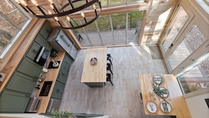 A spacious kitchen with a wooden table, a chandelier, and large windows. - Modern Black Cabin w/ Hot Tub (Burns)