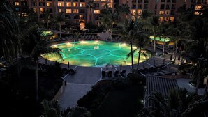 Ett semesterparadis med en swimmingpool omgiven av palmer och en bergskedja i bakgrunden.