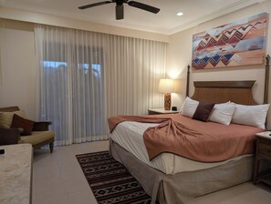 Una habitación de hotel con cama, mesita de noche, lámpara, silla y un cuadro en la pared.