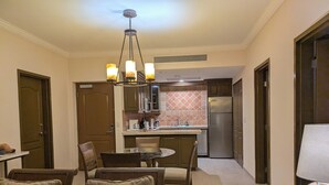 A modern kitchen with a central island, stainless steel appliances, and a dining area with a glass table and cushioned chairs.