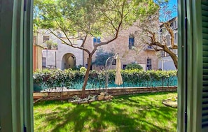 Un cortile con un albero, una poltrona sospesa e un edificio con una finestra e un arco.