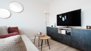 A modern living room with a sofa, coffee table, and TV. - Park Podolski Deluxe Apartment (Łódź)