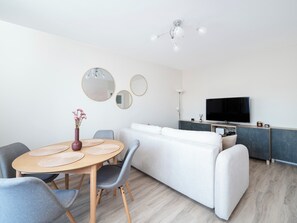 Een moderne woonkamer met een eethoek, een bank, een televisie en een plafondlamp.