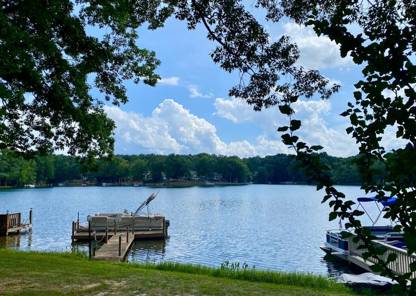 A lake with a dock, boats, and a grassy area.