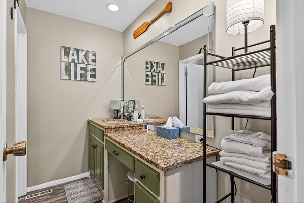 A bathroom with a vanity, towel rack, and two 'LAKE LIFE' signs on the wall.