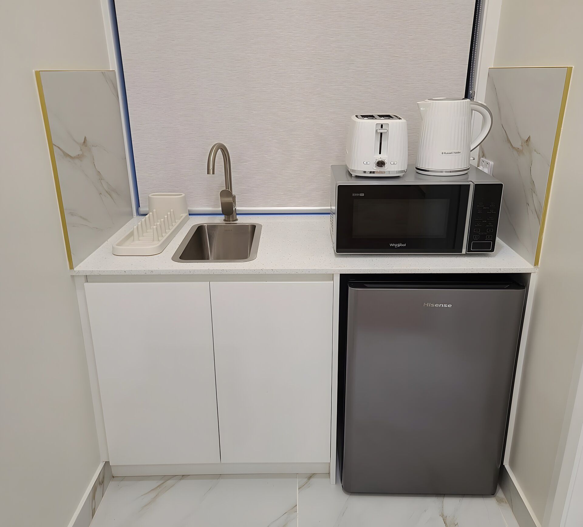 A compact kitchenette with a sink, microwave, and dishwasher.