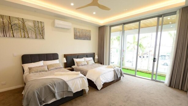 A bedroom with two beds, a ceiling fan, and a large sliding glass door leading to a balcony.