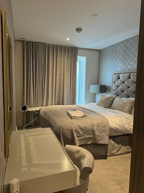 A hotel room with a bed, a bedside table, a lamp, and curtains. - Barking Bliss - Bright Apartment With City Views (Barking)
