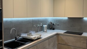 A modern kitchen with a built-in sink, a coffee machine, and a knife block. - Barking Bliss - Bright Apartment With City Views (Barking)