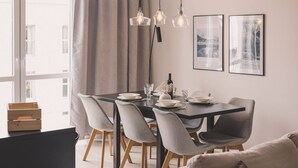 A modern dining area with a dark wooden table, grey upholstered chairs, and pendant lighting. - Humo Pozna Apartament z Klimatyzacj Gara em (Poznań)