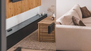 A modern living room with a wooden panel wall, a flat-screen TV, a sofa, and a coffee table. - Humo Pozna Apartament z Klimatyzacj Gara em (Poznań)