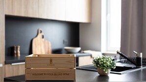 A modern kitchen with wooden cabinetry, a cutting board, a bowl, a potted plant, and a wooden crate with "WELCOME TO YOUR SECOND HOME" engraved on it. - Humo Pozna Apartament z Klimatyzacj Gara em (Poznań)