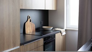 A modern kitchen with wooden cabinets, a black countertop, a wooden cutting board, and a white bowl. - Humo Pozna Apartament z Klimatyzacj Gara em (Poznań)