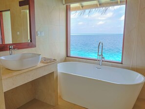 A bathroom with a freestanding bathtub, a sink, and a large window overlooking the ocean. - Cocogiri Island Resort Maldives (Vashugiri)