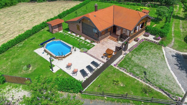 Et stort hus med swimmingpool, udendørs møbler og en velplejet have.